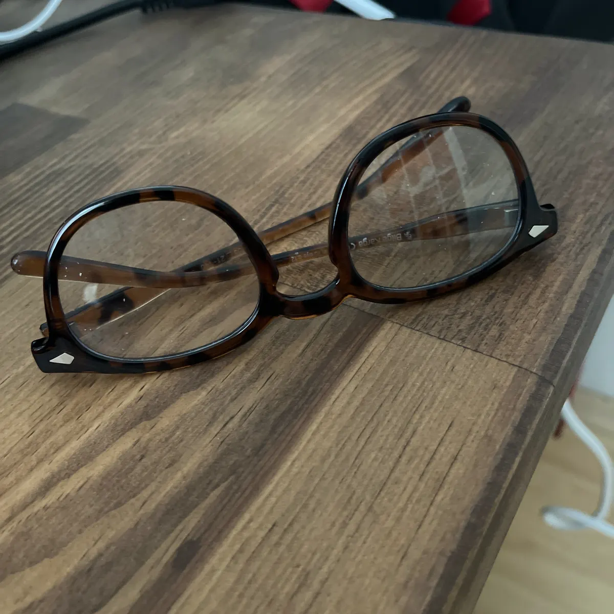Phone photo of tortoiseshell glasses on a cluttered desk, before editing